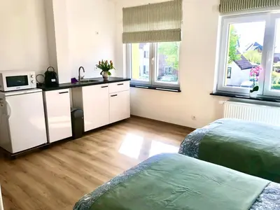 a room with two beds and a kitchen with a microwave at Orange Dolce in Zaventem