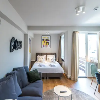 a living room with a bed and a blue couch at Japie rooms - in the heart of Antwerp in Antwerp