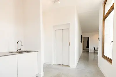 a kitchen with white walls and a sink and a hallway at Luxury Suites South by Rikas Hotels in Antwerp