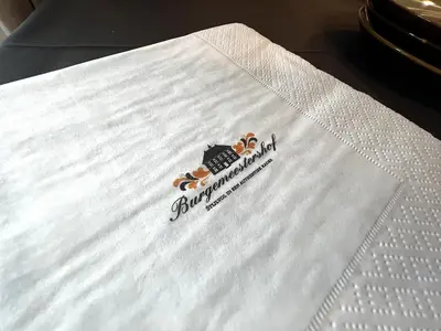 a company logo on a white napkin on a bed at Burgemeestershof in Wetteren