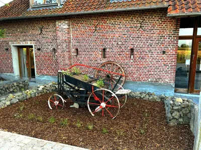 a wagon with plants in it in front of a brick building at Burgemeestershof in Wetteren
