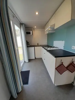 a kitchen with white cabinets and a large window at Vakantiepark Breebos in Rijkevorsel