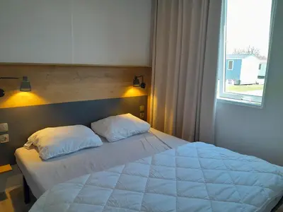 a bed with two pillows in a bedroom with a window at Vakantiepark Breebos in Rijkevorsel