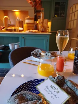 a table with a glass of wine and orange juice at Manoir Hamme in Hamme
