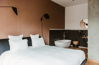 a bedroom with a large bed and a bath tub at Boutique Hotel Marie Marie in Dendermonde