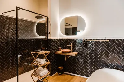 a bathroom with black tiled walls and a mirror at Boutique Hotel Marie Marie in Dendermonde
