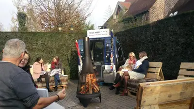 a group of people sitting around a fire grill at Hotel ABBEY in Grimbergen