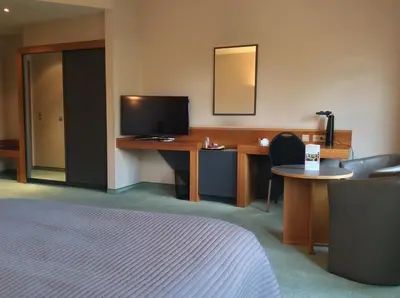 a hotel room with a bed and a desk with a television at Hotel ABBEY in Grimbergen