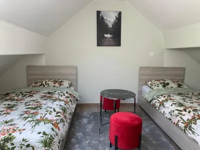 a bedroom with two beds and a table and a stool at Un sommeil paisible in Brussels
