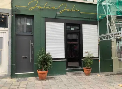 a green building with two potted plants in front of it at Un sommeil paisible in Brussels