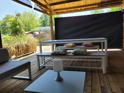 a bench on a porch with pillows on it at Rustig gelegen chalet Solvo met terras aan het water in Geel