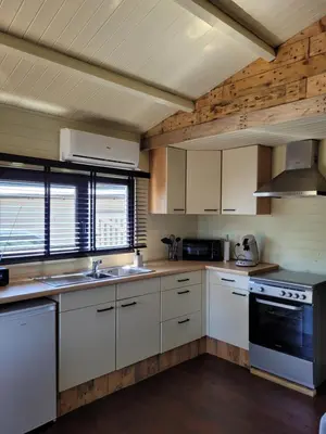 a kitchen with white cabinets and a stove top oven at Rustig gelegen chalet Solvo met terras aan het water in Geel