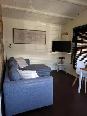 a living room with a couch and a flat screen tv at Rustig gelegen chalet Solvo met terras aan het water in Geel
