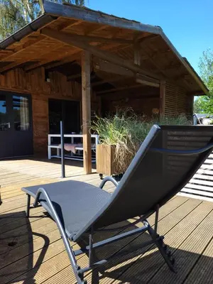 a hammock on a deck in front of a cabin at Rustig gelegen chalet Solvo met terras aan het water in Geel