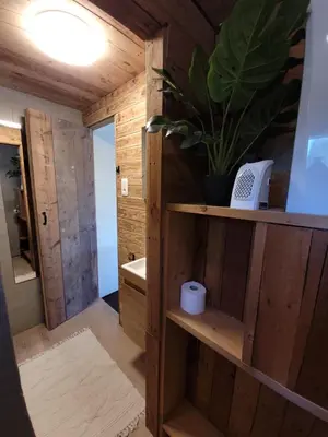 a bathroom with wooden walls and a plant on a shelf at Rustig gelegen chalet Solvo met terras aan het water in Geel