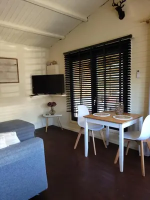 a living room with a table and chairs and a tv at Rustig gelegen chalet Solvo met terras aan het water in Geel