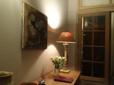 a lamp on a table with a vase of flowers at Guesthouse Alizée in Leuven