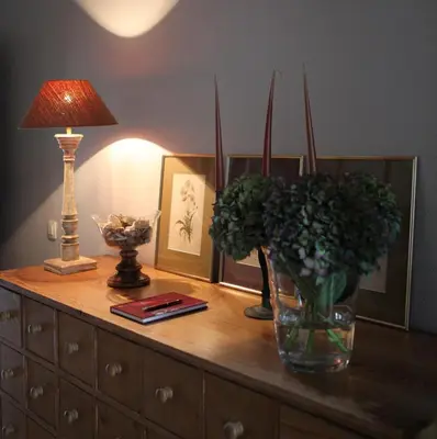 a dresser with a vase of flowers and a lamp at Guesthouse Alizée in Leuven