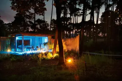 a small house with lights in a yard at night at Nooz - Something Different? in Grobbendonk