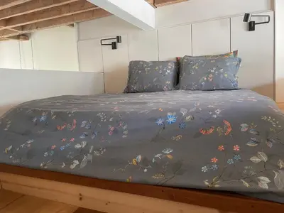 a bed with a blue blanket with flowers on it at Perfect location & Parking in Antwerp