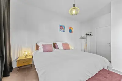 a white bedroom with a large white bed with pink pillows at Central & luminous apartment in Antwerp