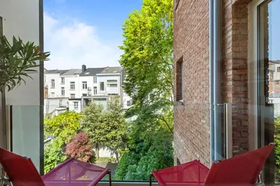 a group of red chairs on a balcony looking out a window at Central & luminous apartment in Antwerp