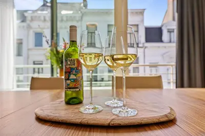 two glasses of white wine sitting on a wooden table at Central & luminous apartment in Antwerp