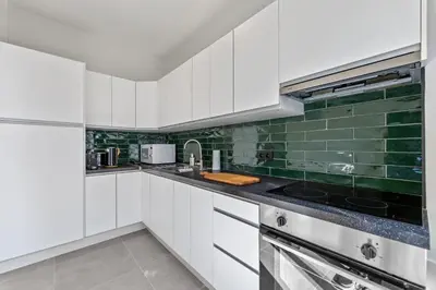 a kitchen with white cabinets and green tiles at Central & luminous apartment in Antwerp