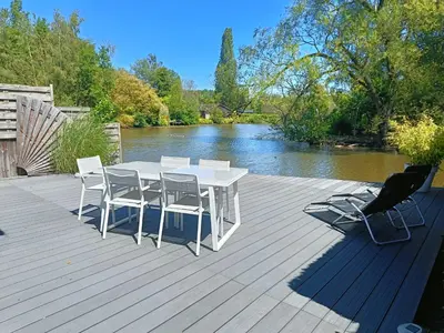 a white table and chairs on a deck next to a river at Time 2 Relax chalet aan het water in Geel
