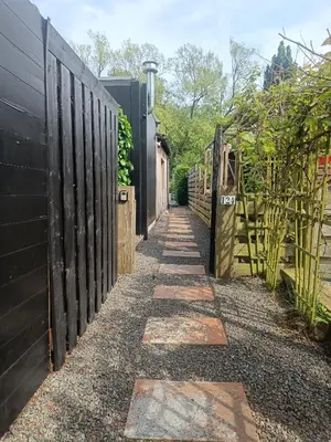 a walkway in a garden with a fence at Time 2 Relax chalet aan het water in Geel