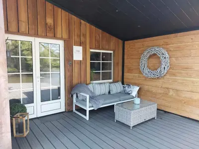a porch with a couch and a wreath on a wooden wall at Time 2 Relax chalet aan het water in Geel