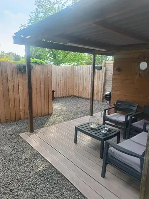 a pergola with a table and chairs on a deck at Time 2 Relax chalet aan het water in Geel