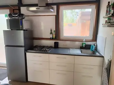 a small kitchen with a refrigerator and a sink at Time 2 Relax chalet aan het water in Geel
