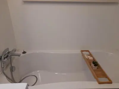 a bathroom with a bath tub with a wooden shelf at Oud-Turnhout Nature Chalet in Oud-Turnhout