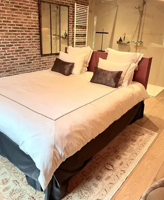 a large bed in a room with a brick wall at Domaine Bourgogne en Grez 