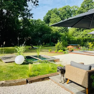 a dog standing next to a chair and an umbrella at Domaine Bourgogne en Grez 