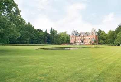 a large house with a pond in a large grass field at Gravenhof in Beersel