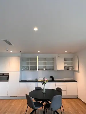 a kitchen with white cabinets and a table and chairs at ApartHotel Dénia in Lochristi