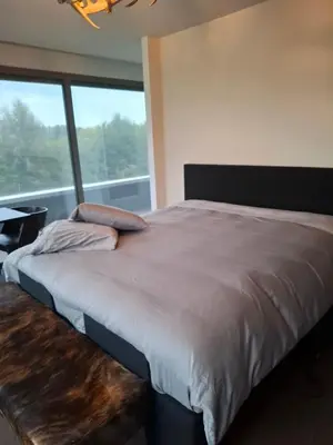 a bedroom with a large bed and a large window at B&B Finis terrae in Lokeren