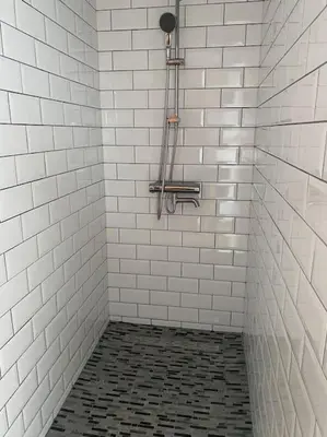 a white tiled shower with a black and white tile floor at Spacious app/Antwerp city center #003 in Antwerp
