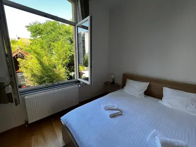 a bedroom with a white bed and a large window at L&L Residence 1 in Brussels