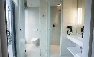 a white bathroom with a toilet and a shower at OPO Hotel in Brussels