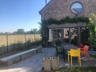 a patio with chairs and a table in front of a building at landelijke villa met zwembad en gezellige openhaard in Zemst