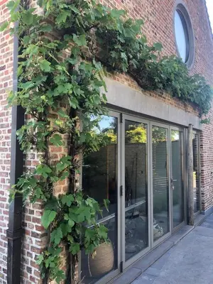 a building with a large window with plants on it at landelijke villa met zwembad en gezellige openhaard in Zemst
