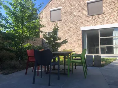 a table and chairs in front of a brick building at landelijke villa met zwembad en gezellige openhaard in Zemst