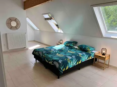 a bedroom with a bed with blue sheets and a window at House Botanique in Meise