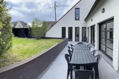 a patio with a wooden table and chairs and a yard at House Botanique in Meise