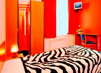a zebra print bed in a bedroom with red curtains at Hotel The Moon in Brussels