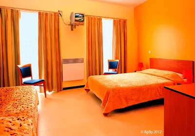 a bedroom with two beds and two chairs and a television at Hotel The Moon in Brussels