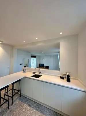 a kitchen with white cabinets and a large mirror at Sunny apartment @theater area in Antwerp